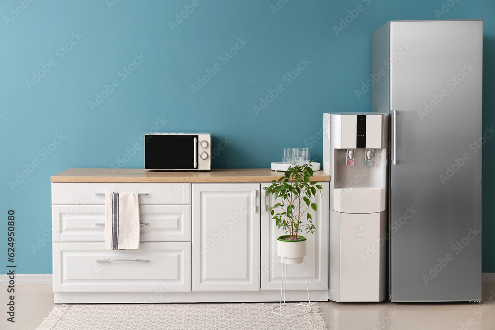 Interior of kitchen with modern water cooler near blue wall