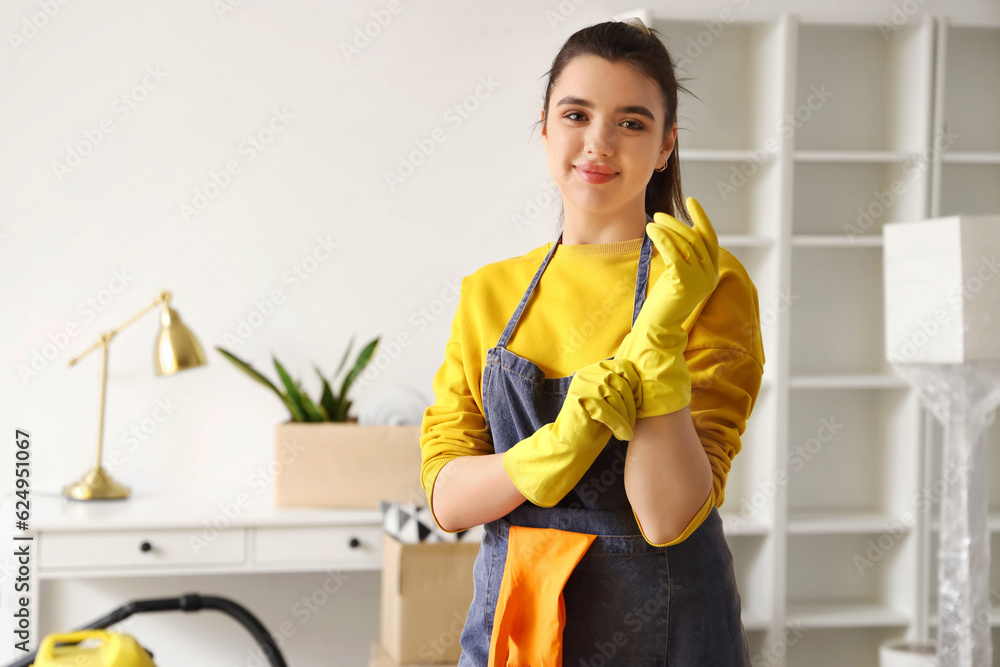 Young woman putting on rubber gloves before cleaning her house