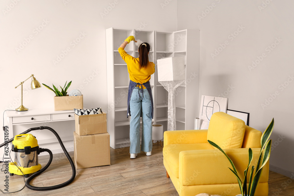 Young woman with pp-duster cleaning her house