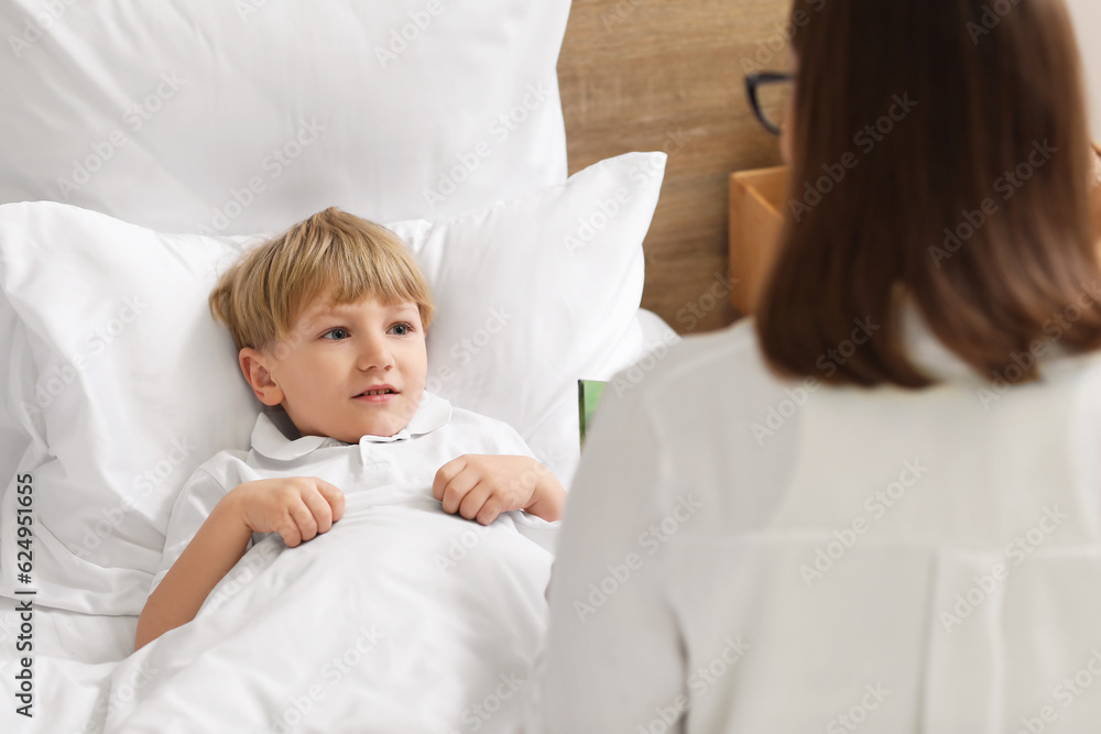 Nanny reading story to little boy in bedroom