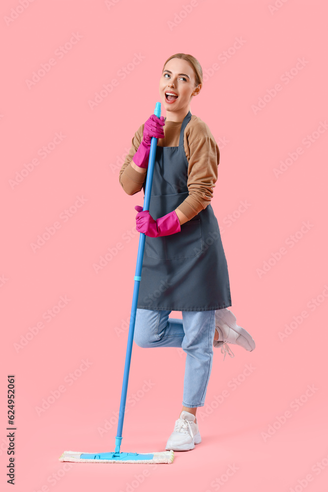 Young woman with mop singing on pink background