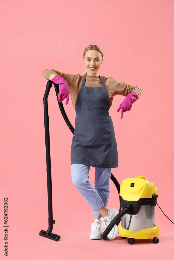 Young woman with vacuum cleaner on pink background