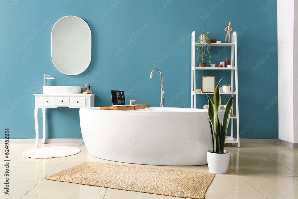 Interior of bathroom with bathtub, modern laptop and mirror