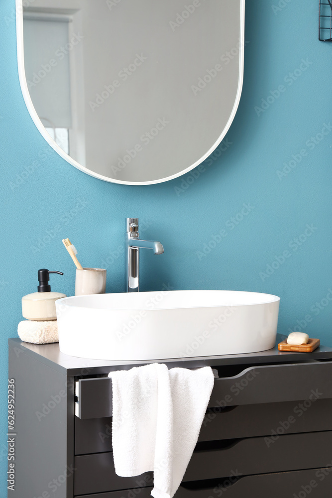 Sink and bathing accessories on dressing table near blue wall