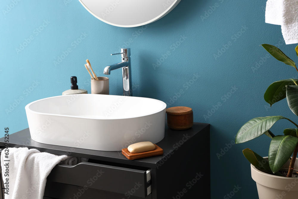 Sink and bathing accessories on dressing table near blue wall