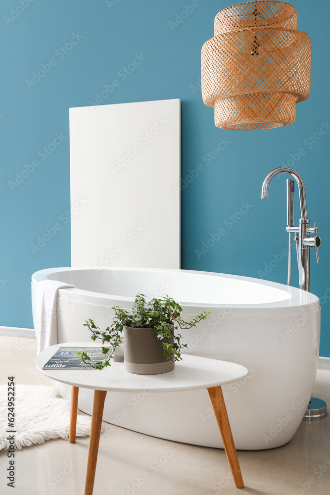 Interior of bathroom with bathtub and houseplant on coffee table