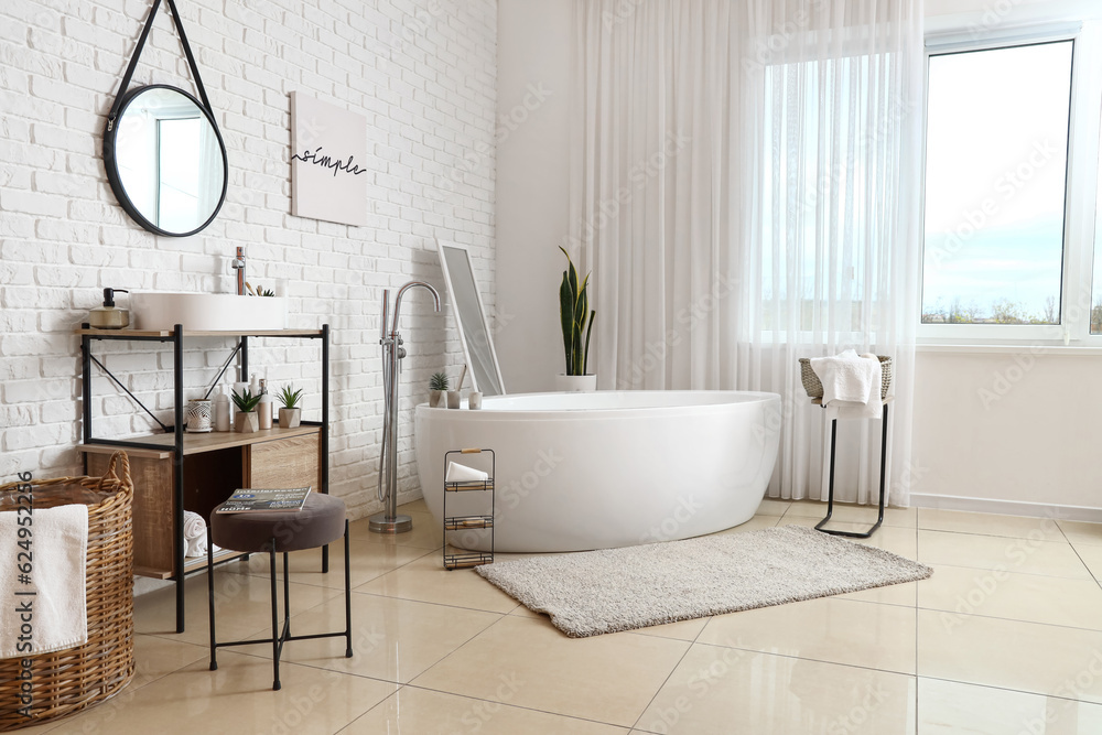 Interior of stylish bathroom with bathtub, dressing table, sink and mirror