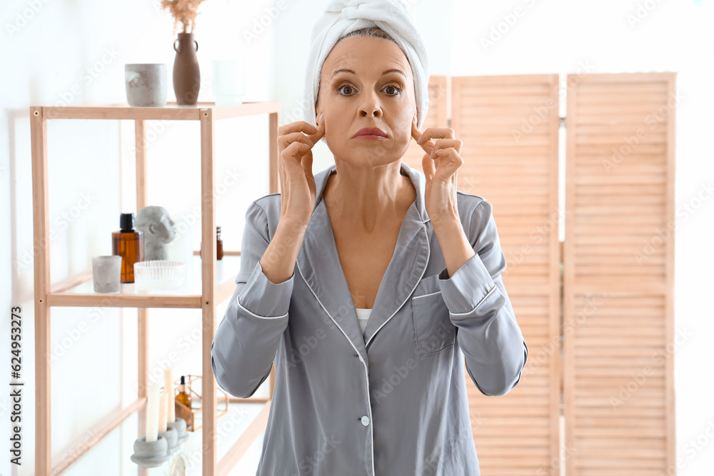 Mature woman doing face building exercise in bathroom