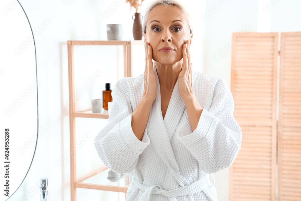 Mature woman doing face building exercise in bathroom