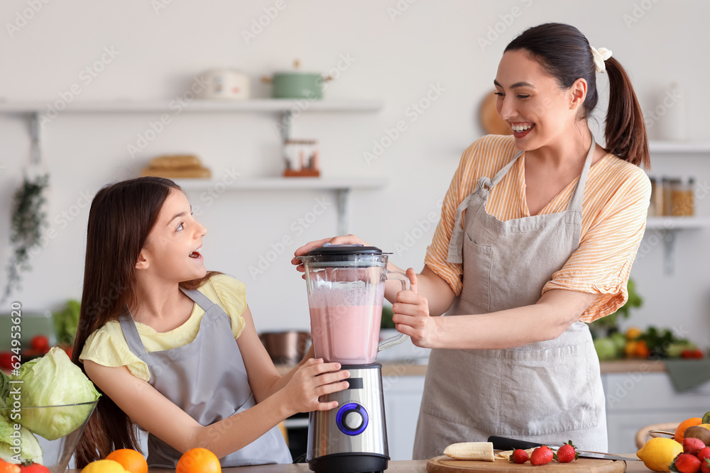 Little girl and her mother making smoothie with blender in kitchen