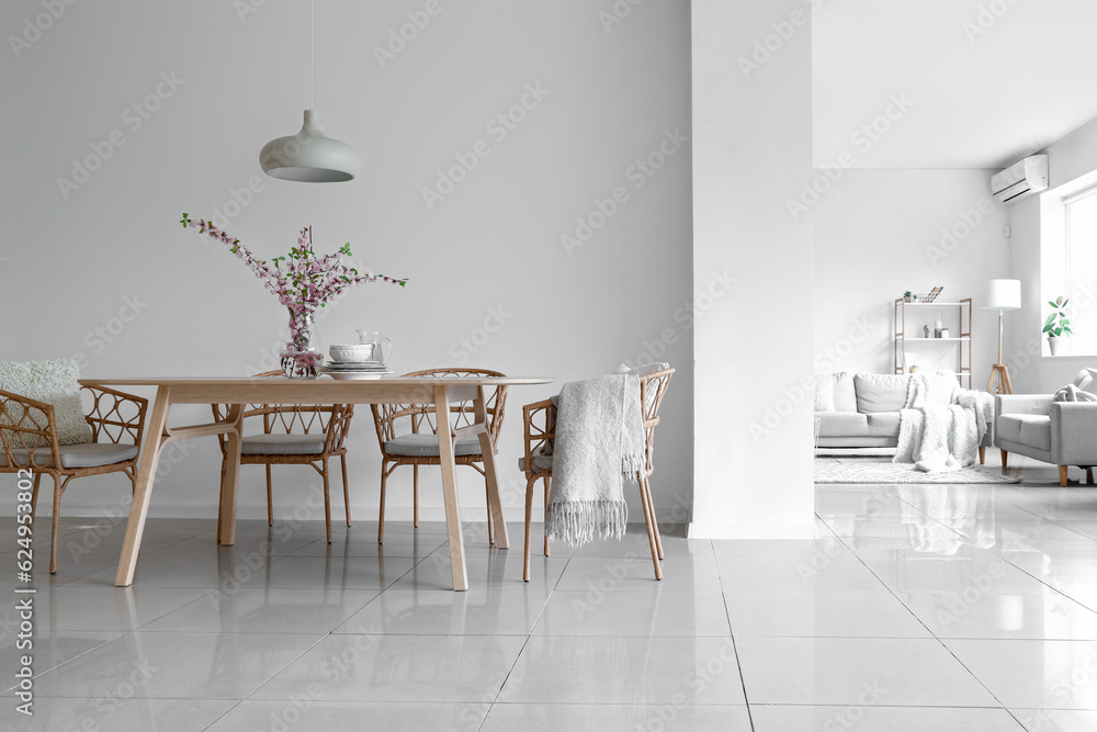 Interior of stylish dining room with blooming sakura branches on table