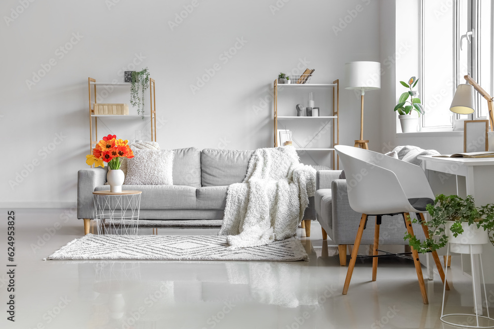 Interior of light living room with cozy sofas and tulip flowers on coffee table