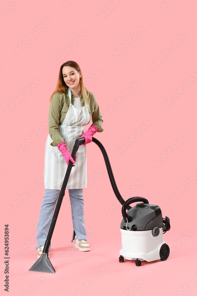 Young woman with vacuum cleaner on pink background