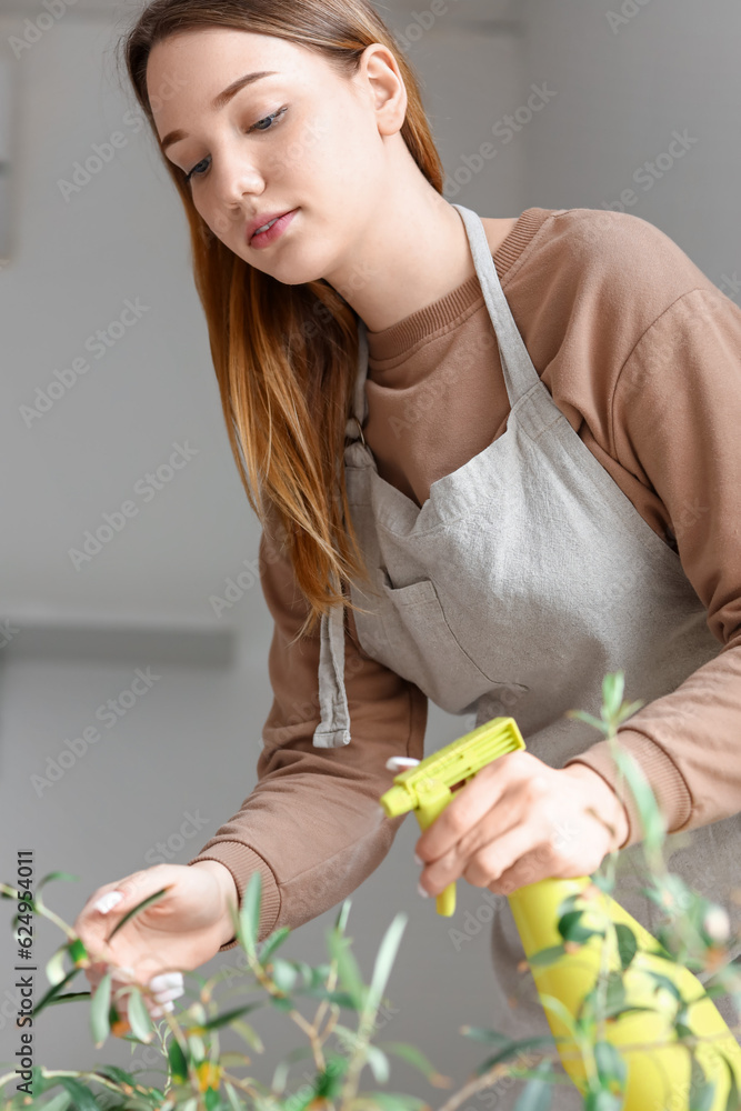 Young woman spraying water onto houseplant in bedroom