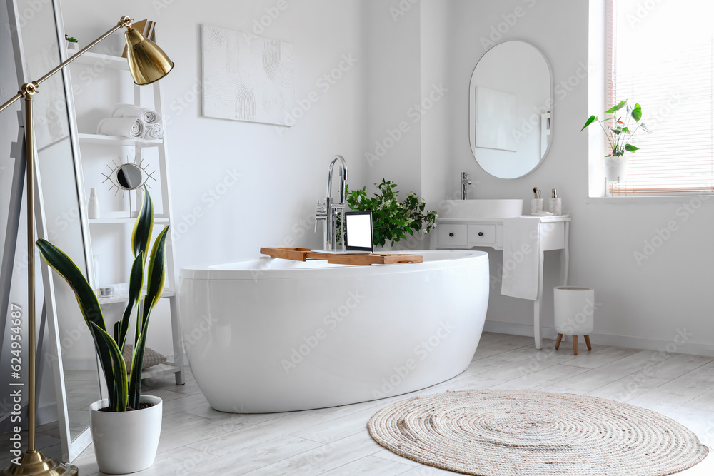 Interior of light bathroom with bathtub, dressing table and shelving unit