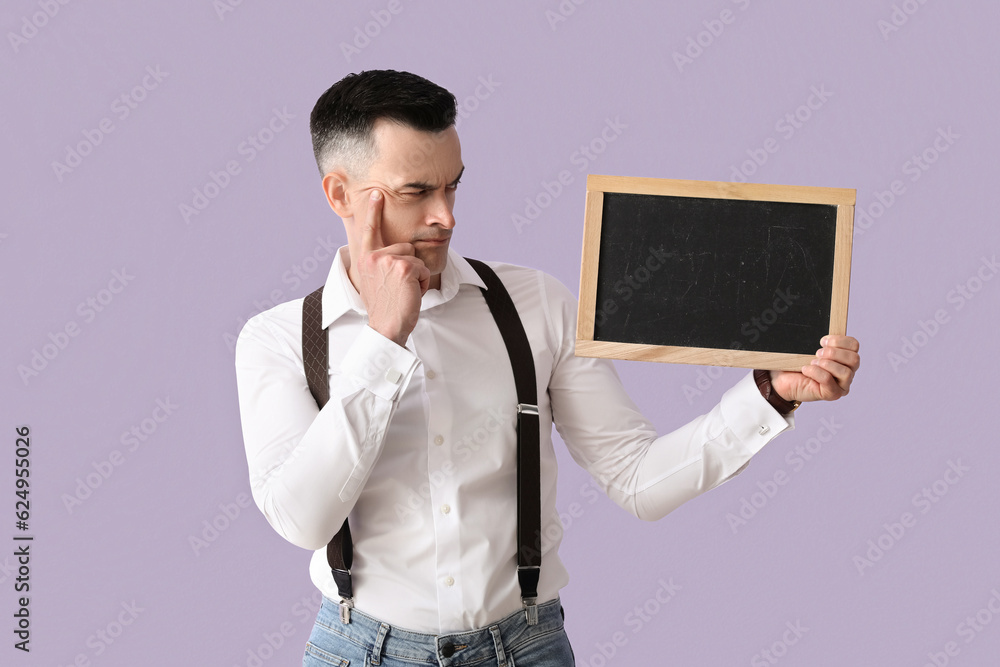 Thoughtful male teacher with chalkboard on lilac background