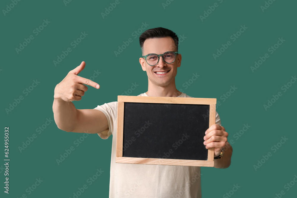 Male teacher pointing at chalkboard on green background