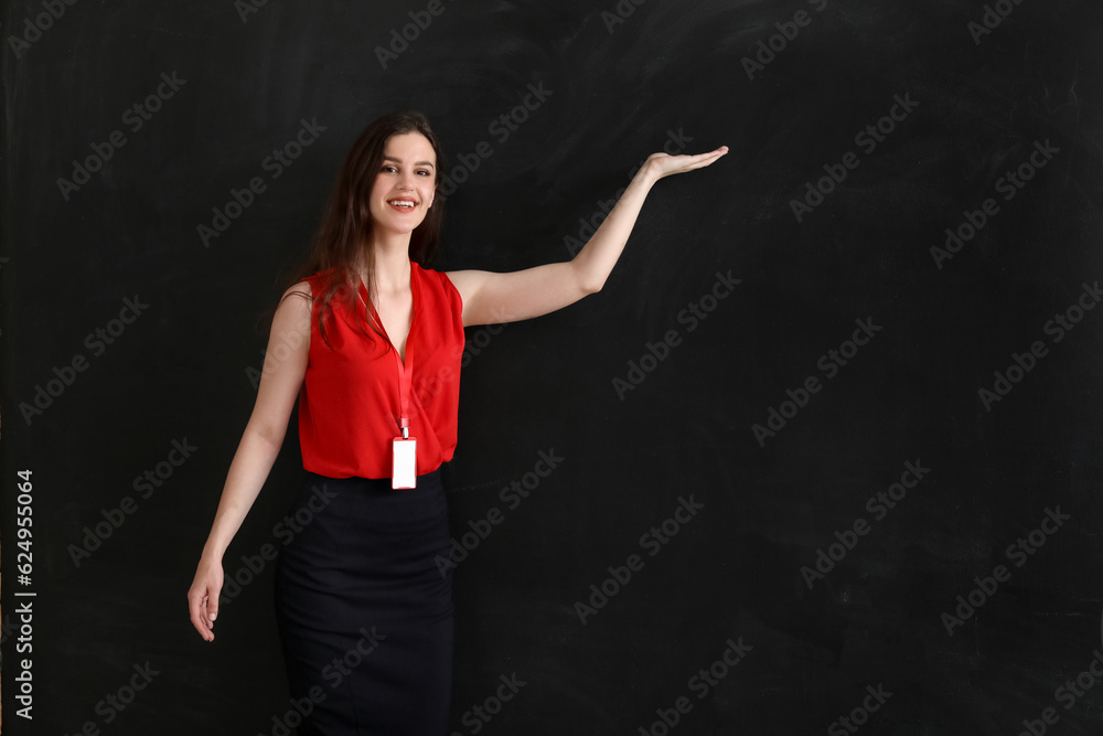 Female teacher showing something on blackboard in classroom