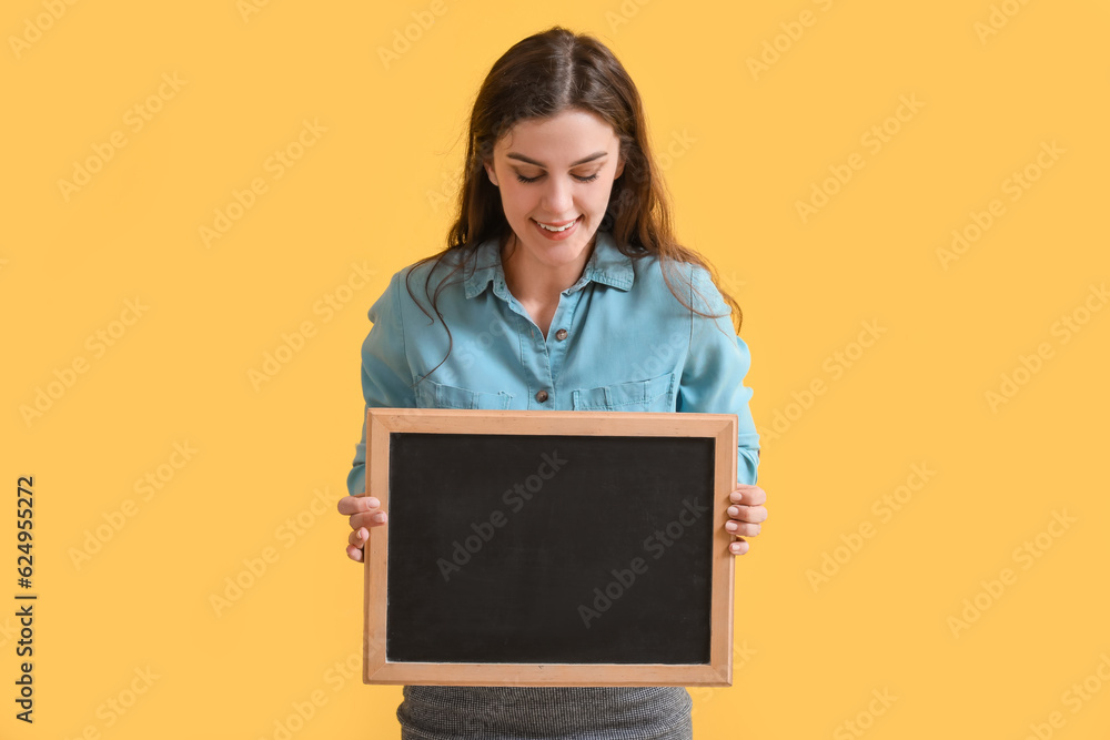 Female teacher with chalkboard on yellow background