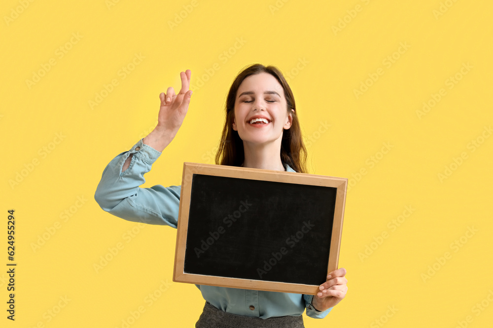 Female teacher with chalkboard pointing at something on yellow background