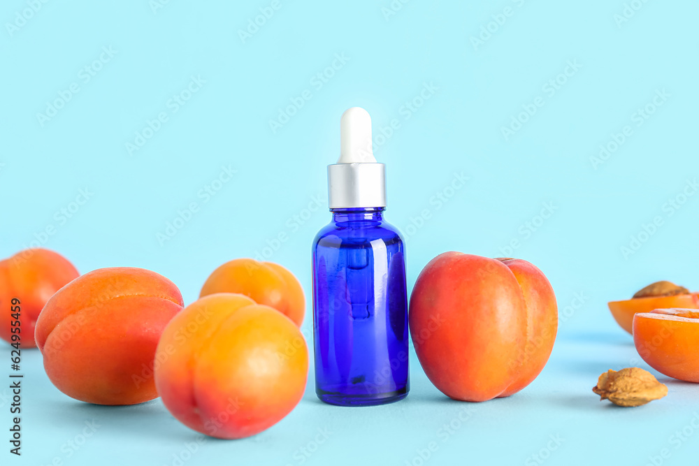 Bottle of essential oil and ripe apricots on color background