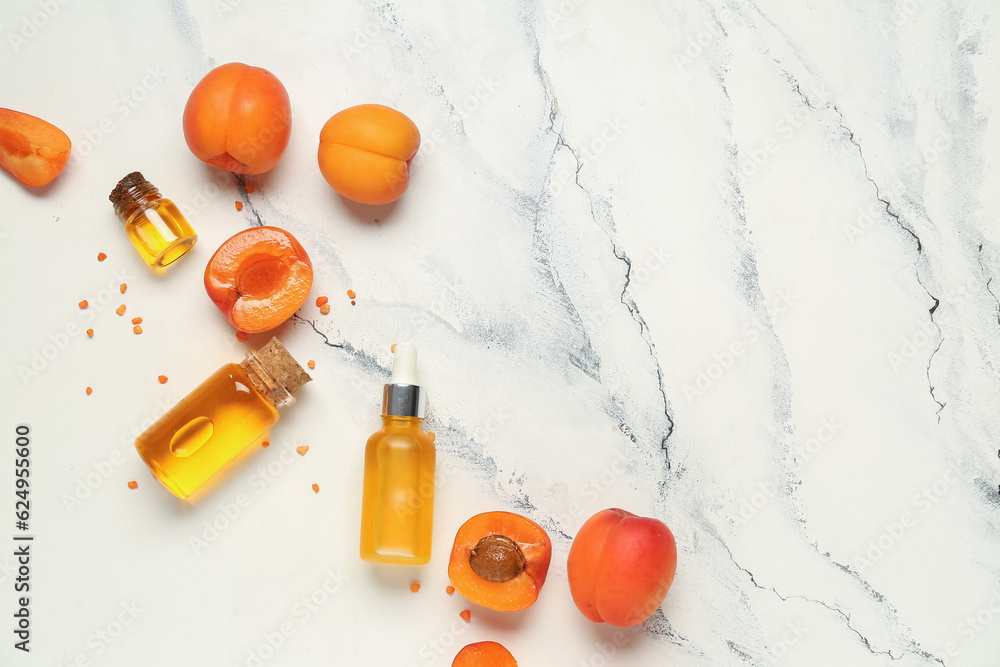 Composition with bottles of essential oil and apricots on light background