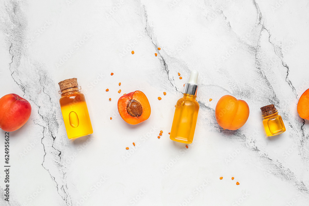 Composition with bottles of essential oil and ripe apricots on light background