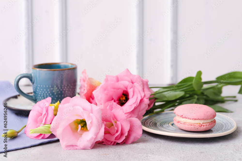 Beautiful pink eustoma flowers, plate with macaroon and cup of coffee on white table