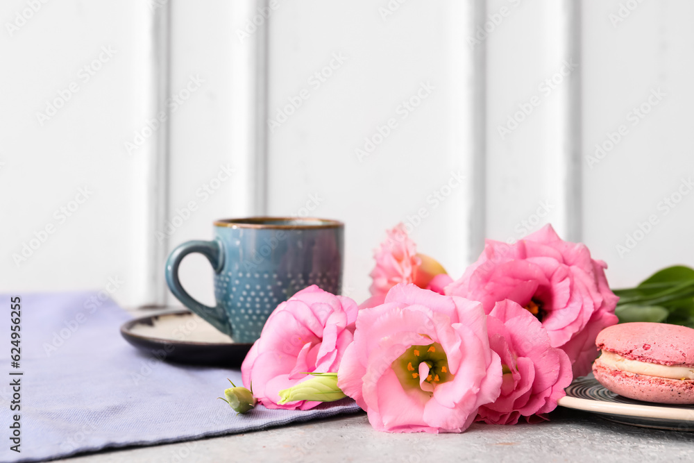 Beautiful pink eustoma flowers, plate with macaroon and cup of coffee on white table