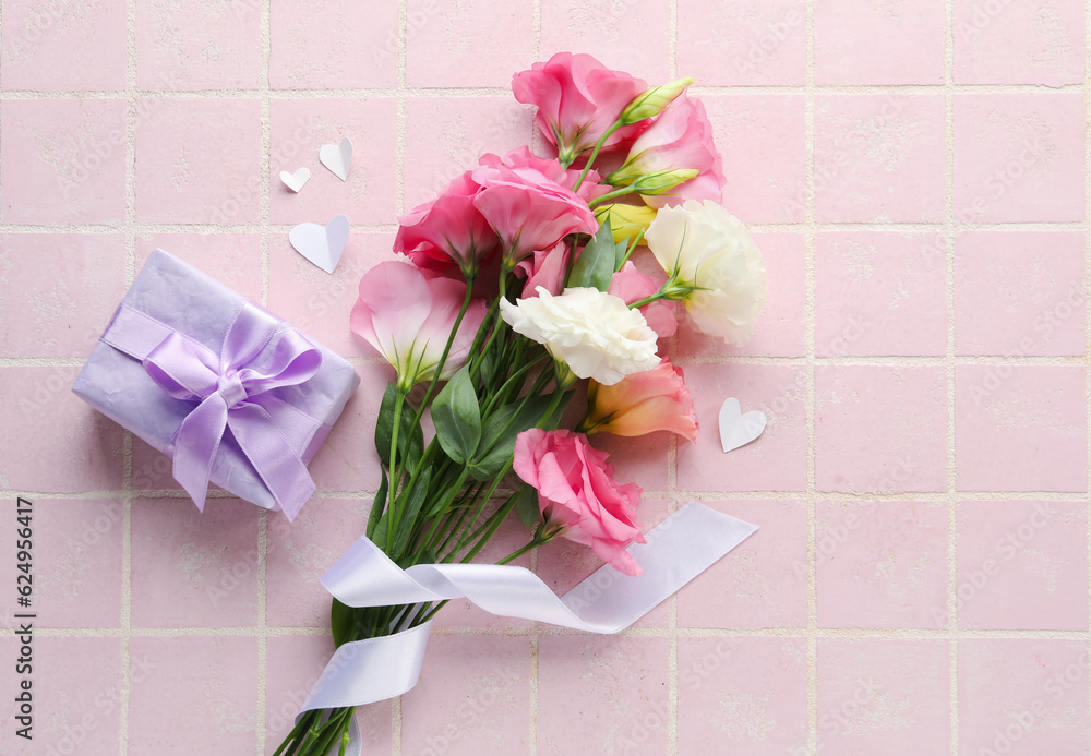 Bouquet of beautiful pink eustoma flowers and gift box on light tile background