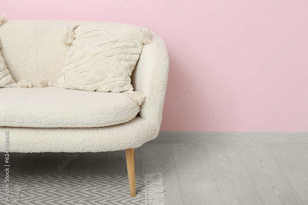 Cozy white sofa with pillows near pink wall