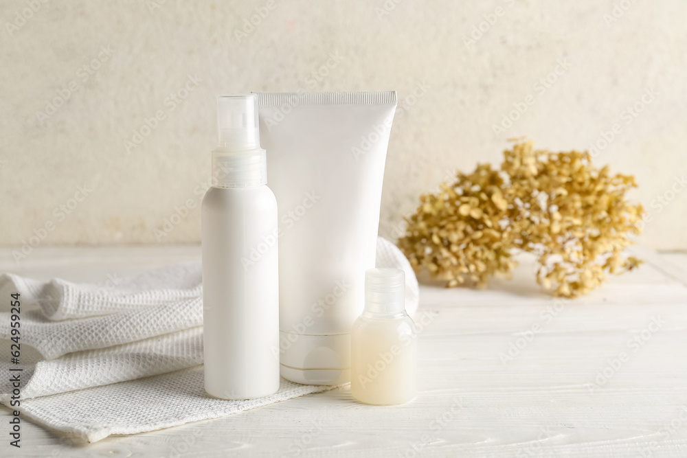 Set of cosmetic products, clean towel and dried hydrangea on light background