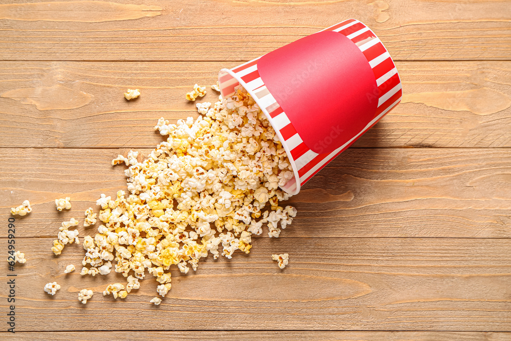 Bucket with tasty popcorn on wooden background