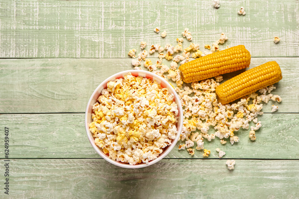 Bucket with tasty popcorn on green wooden background