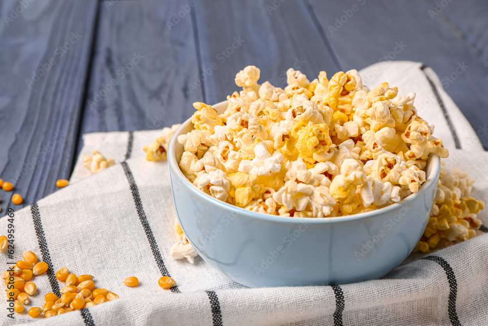 Bowl with tasty popcorn on blue wooden background