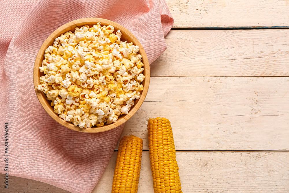 Bowl with tasty popcorn on white wooden background