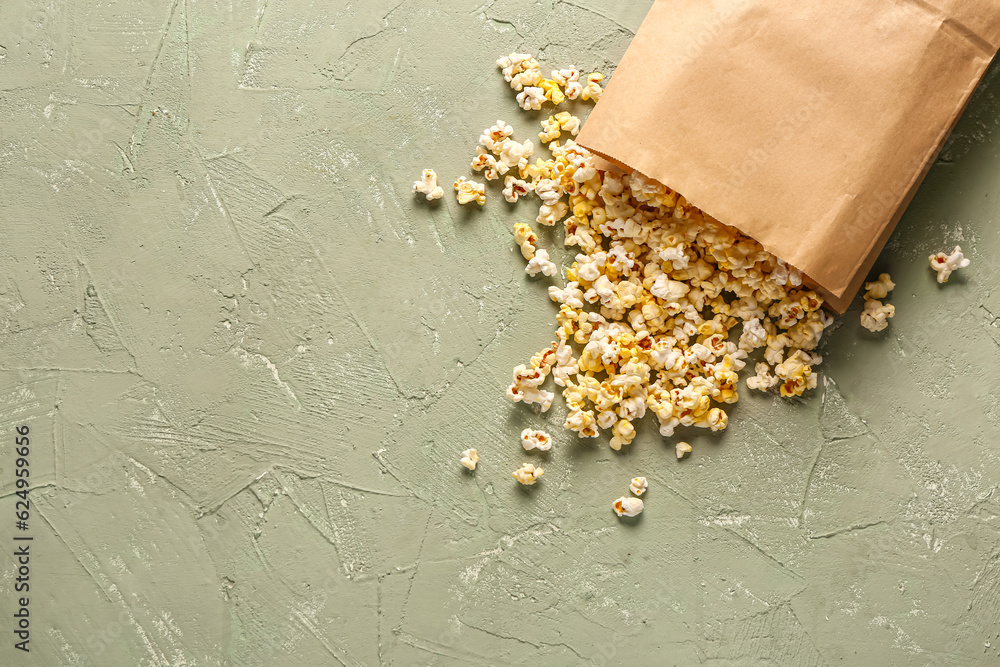 Paper bag with tasty popcorn on grey background