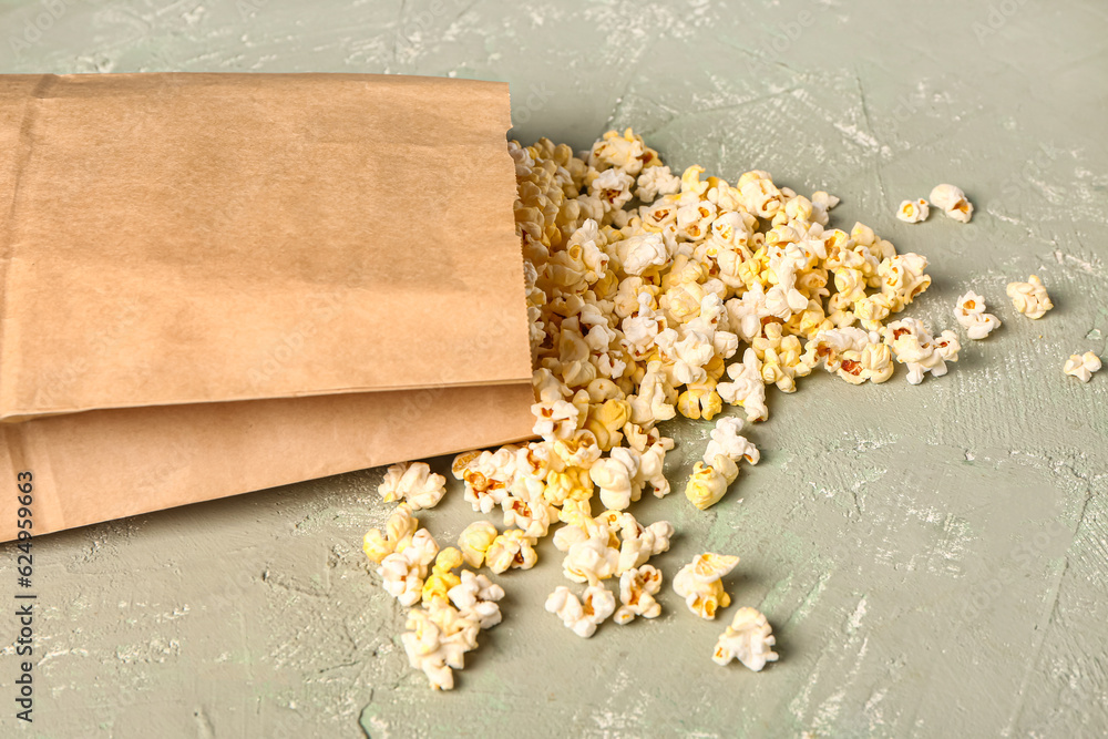 Paper bag with tasty popcorn on grey background