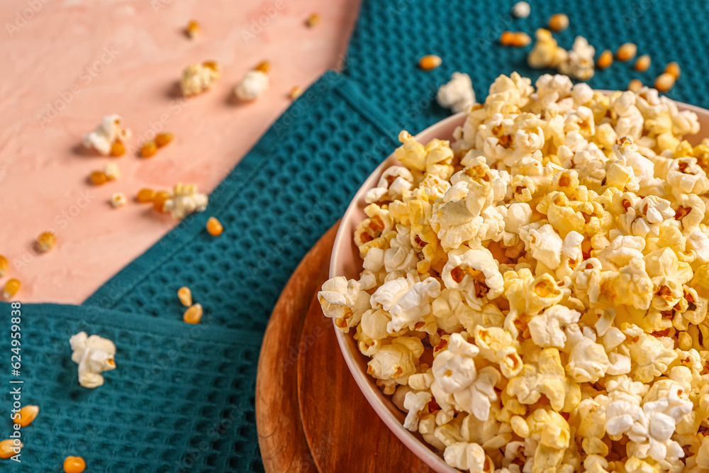 Bowl with tasty popcorn and seeds on pink background