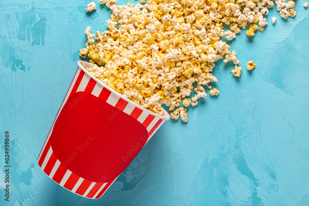 Bucket with tasty popcorn on blue background