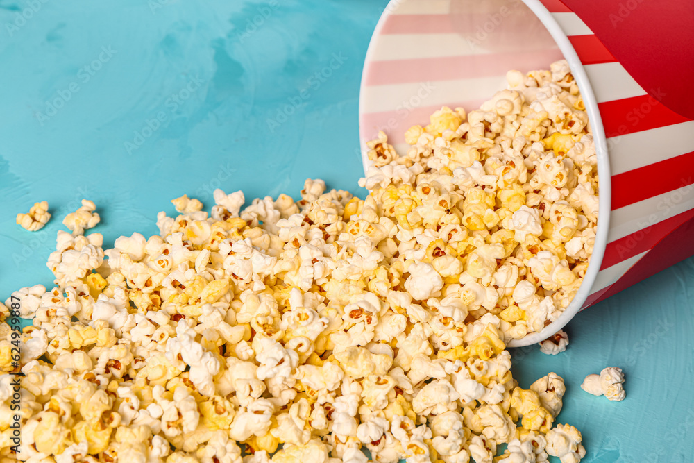 Bucket with tasty popcorn on blue background