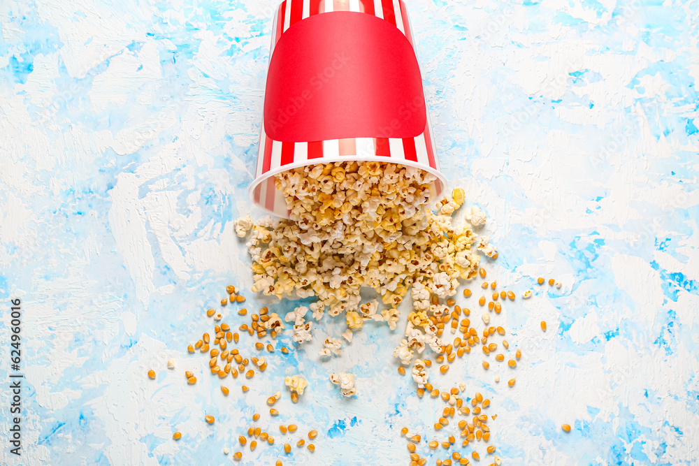 Bucket with tasty popcorn on light blue background