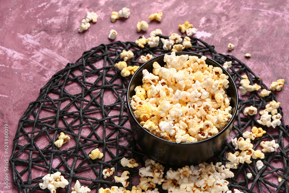 Bowl with tasty popcorn on purple background