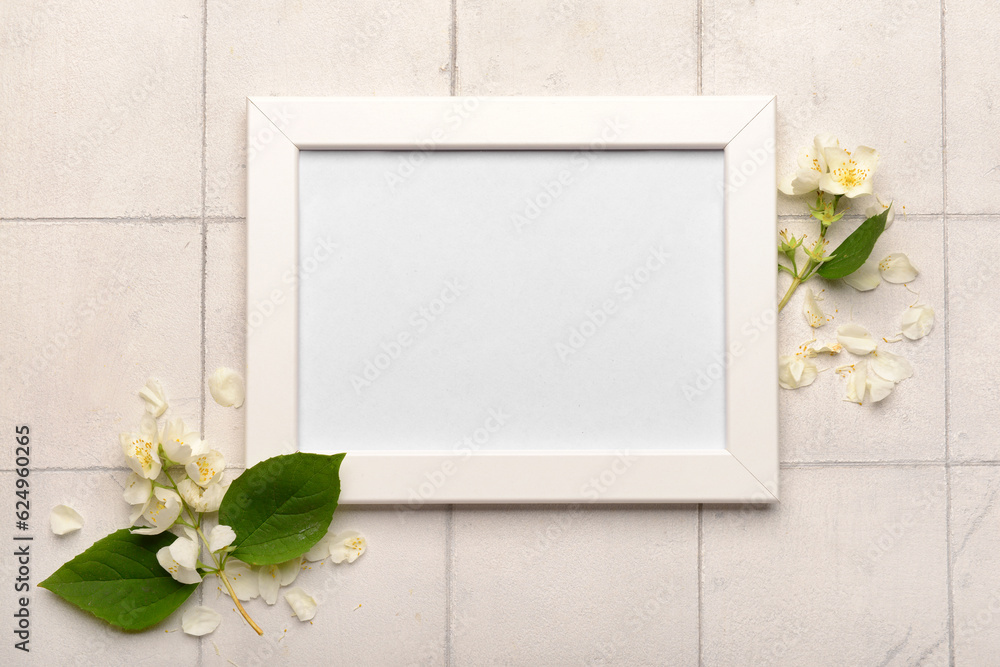 Blank photo frame and beautiful flowers on white tile background