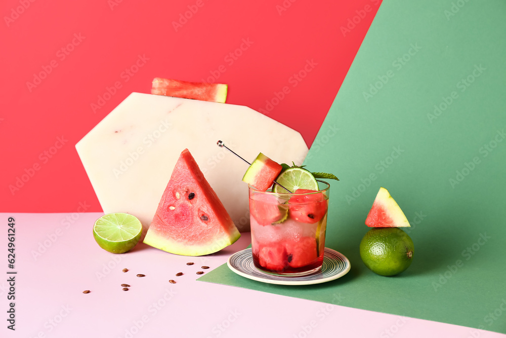 Glass of fresh watermelon lemonade with lime and mint on colorful background