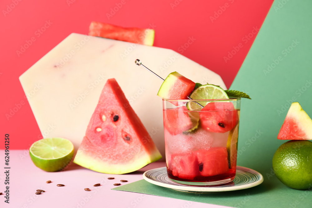 Glass of fresh watermelon lemonade with lime and mint on colorful background