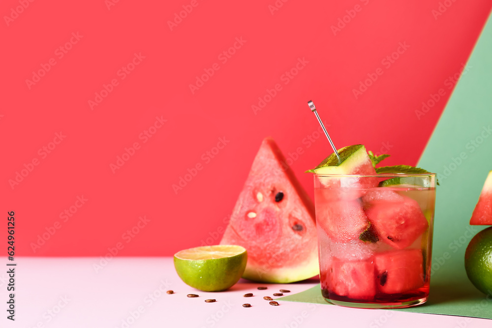 Glass of fresh watermelon lemonade with lime and mint on colorful background