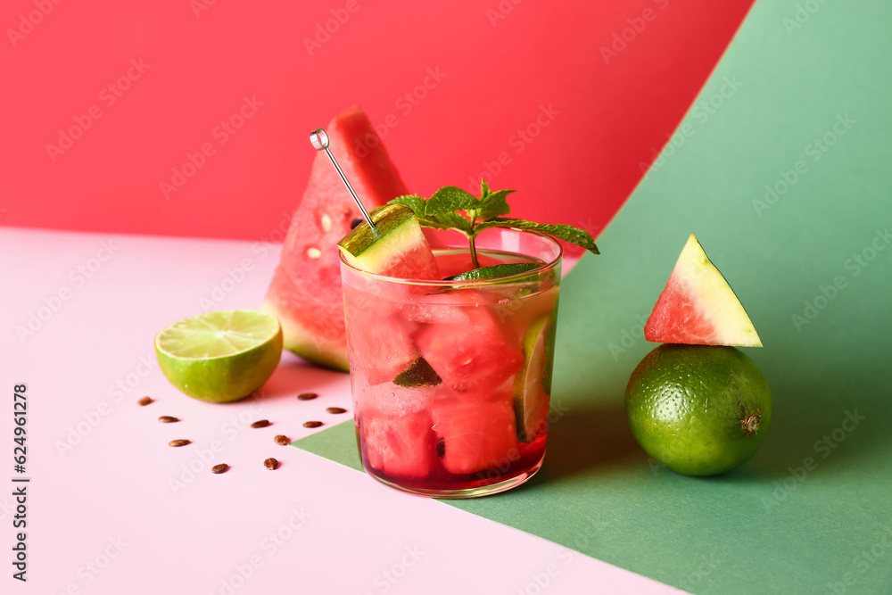 Glass of fresh watermelon lemonade with lime and mint on colorful background