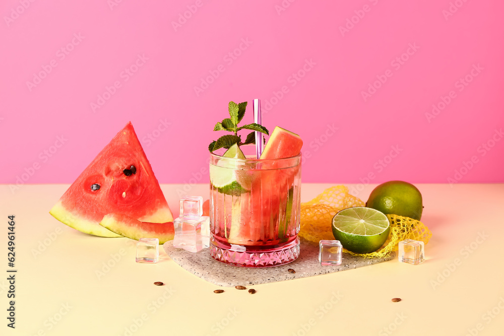 Glass of fresh watermelon lemonade with lime and mint on yellow table