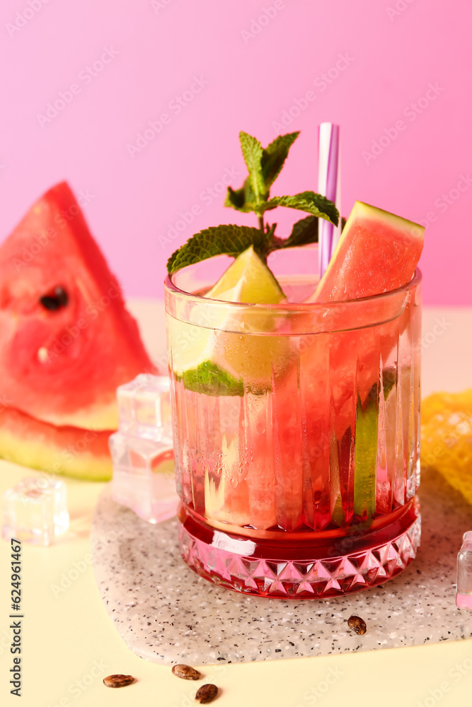 Glass of fresh watermelon lemonade with lime and mint on yellow table